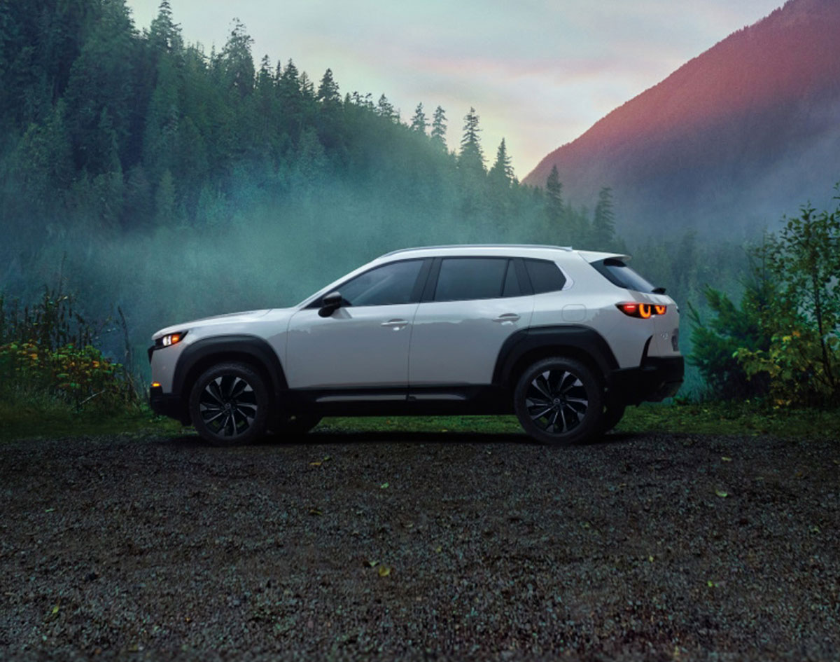 Silver 2026 Mazda CX-50 facing left with a backdrop of mountains and forest near Longview, TX