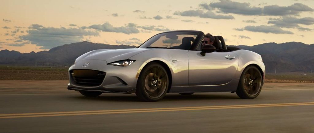 Mazda MX-5 Miata convertible driving on a road.