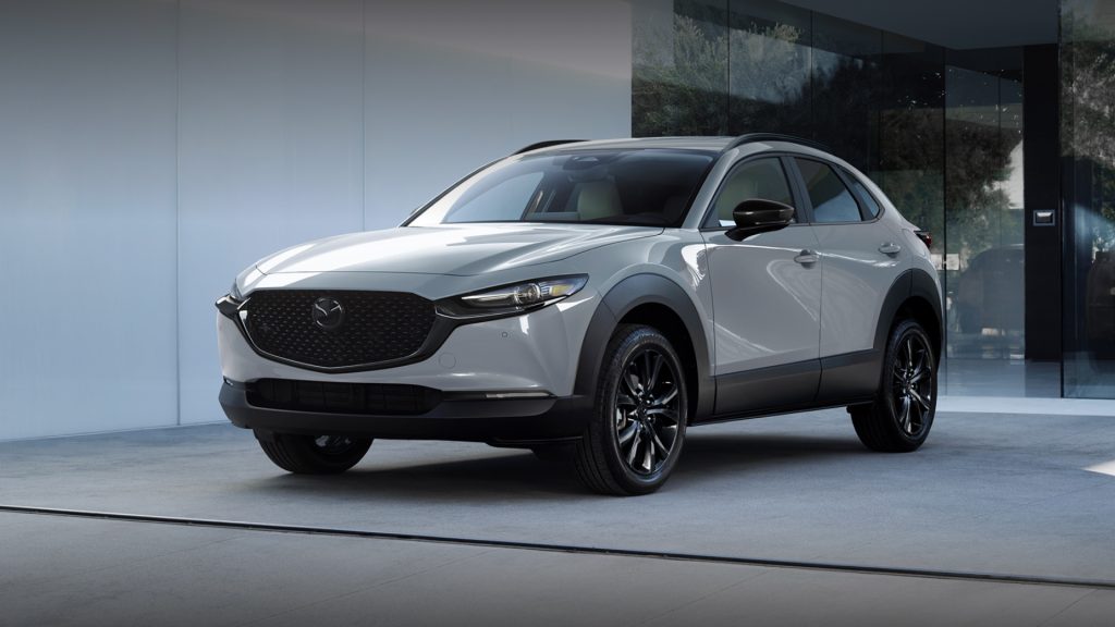 White Mazda CX-30 parked outside a modern building.