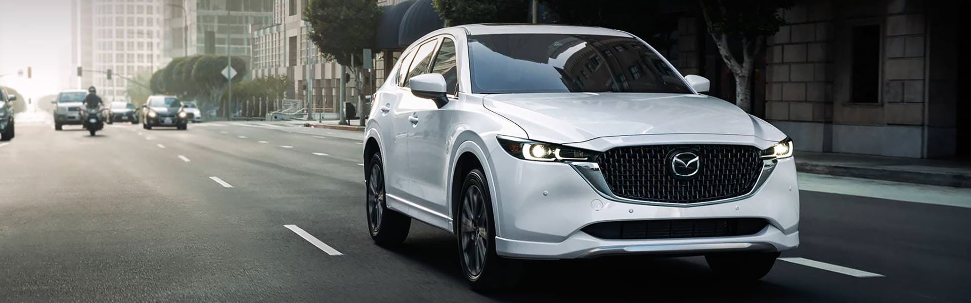 White Mazda SUV driving through a city street.